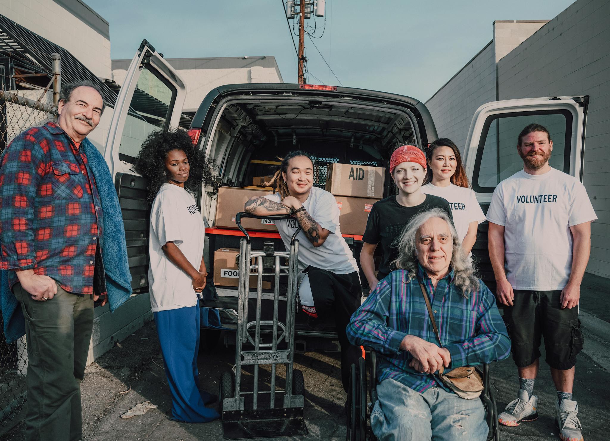 A diverse group of volunteers packing aid supplies into a van for donation.