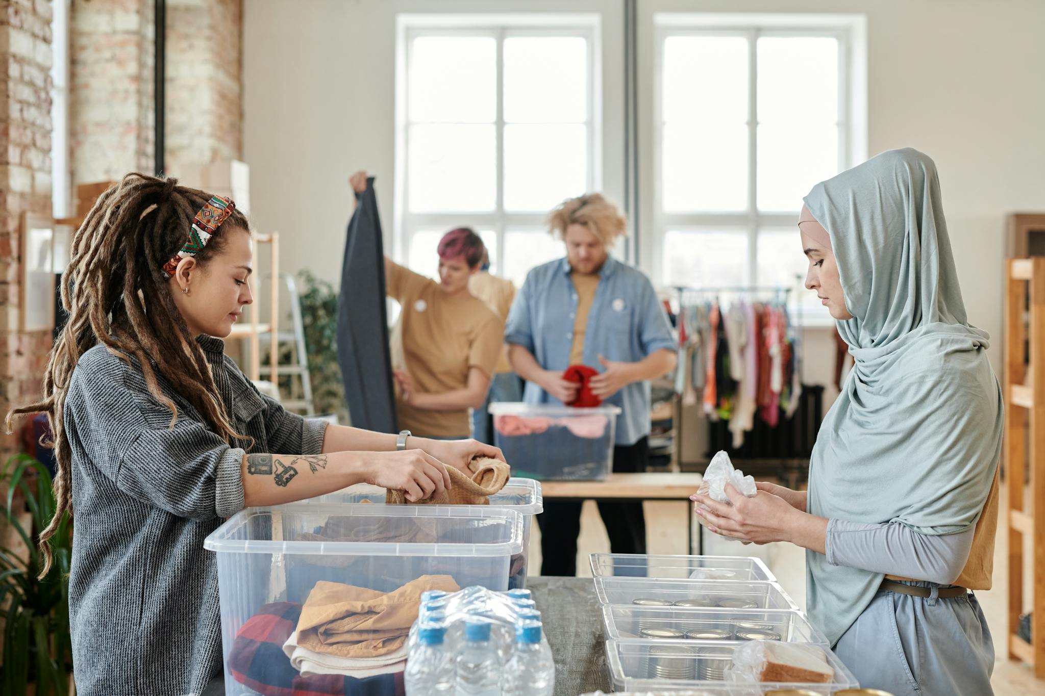 Volunteers organizing donated clothes in an indoor setting for charity work.